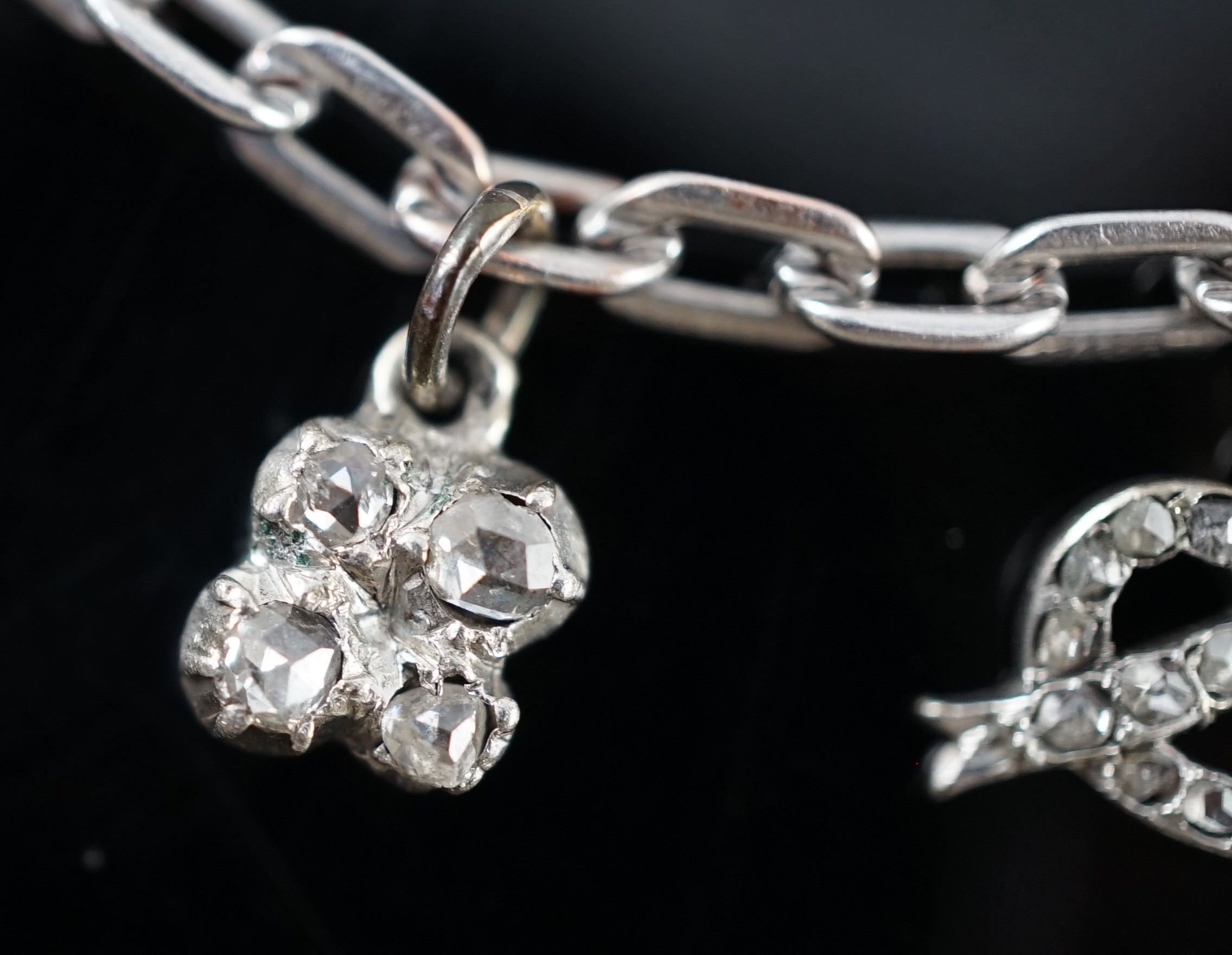 A 9ct white gold charm bracelet, with French platinum and diamond set clasp and hung with nine assorted charms, eight set with diamonds